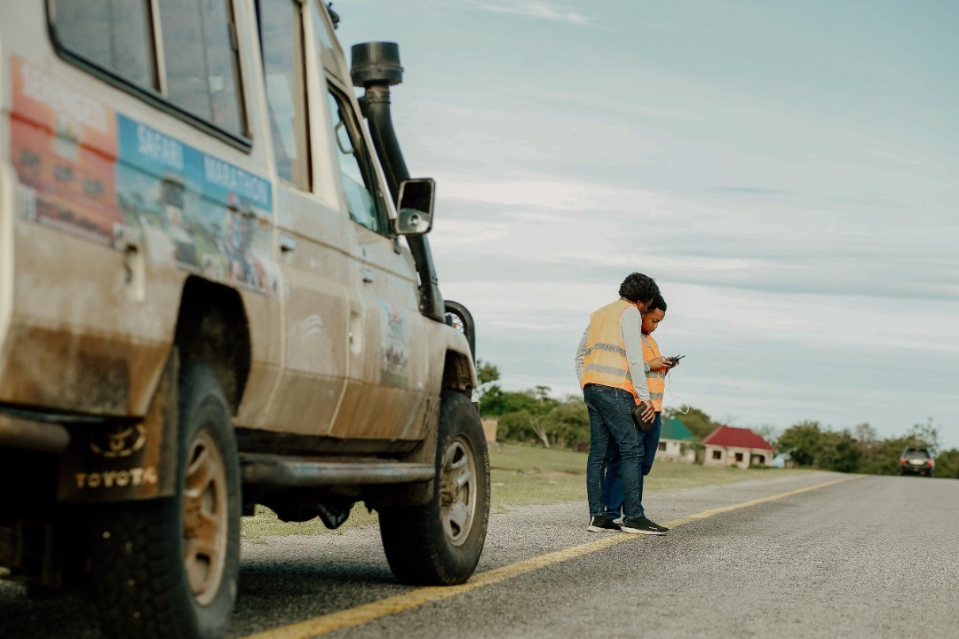 A picture of Mirambo Paul on the side of the road giving directions to a drone pilot.